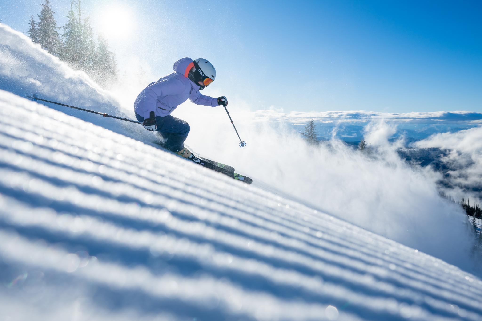 Woman skiing high above the clouds on groomed slopes in Sun Peaks