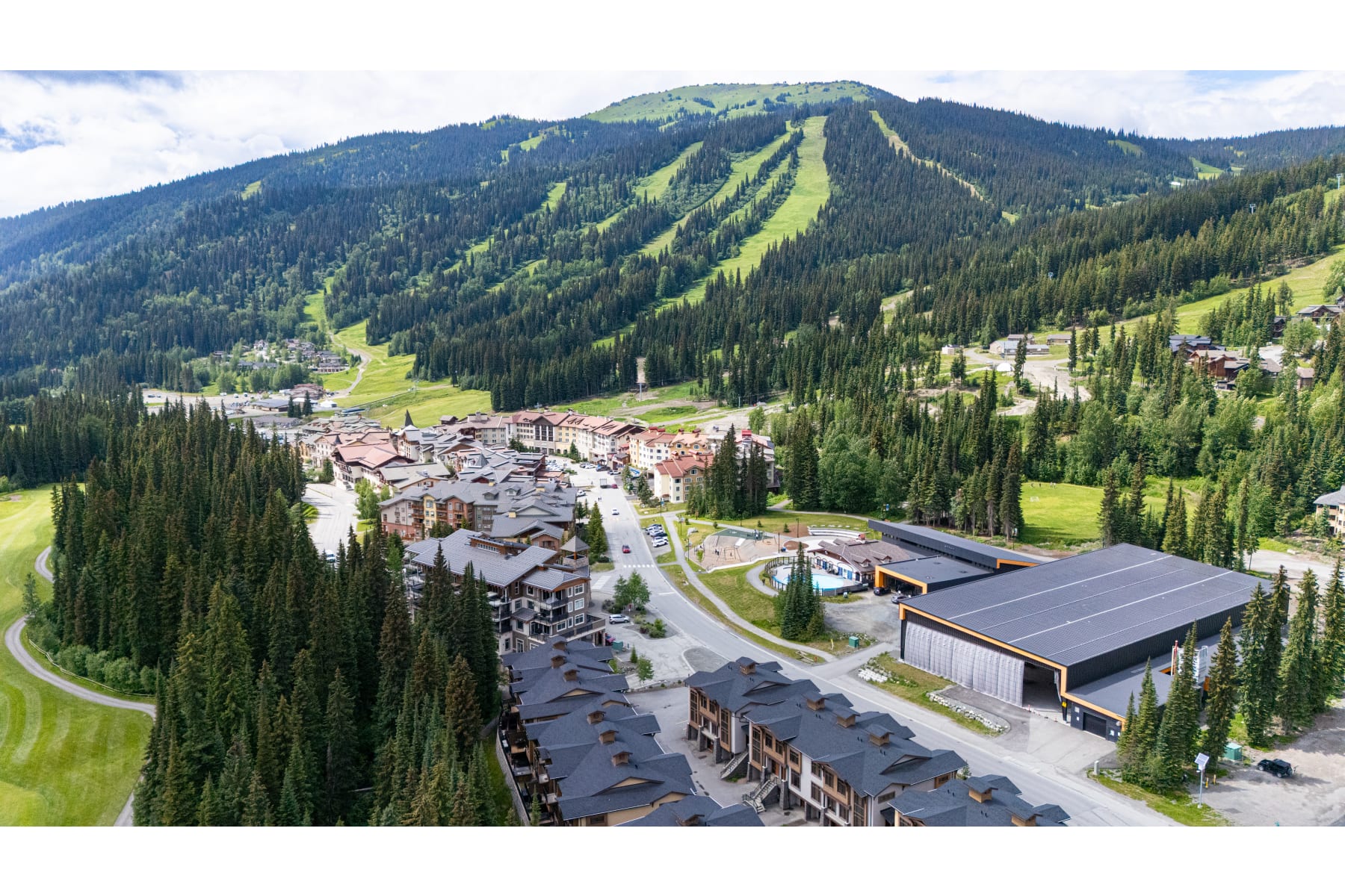 Sun Peaks Centre and Sun Peaks Centre Stage in front of a green Mt. Tod in summer.