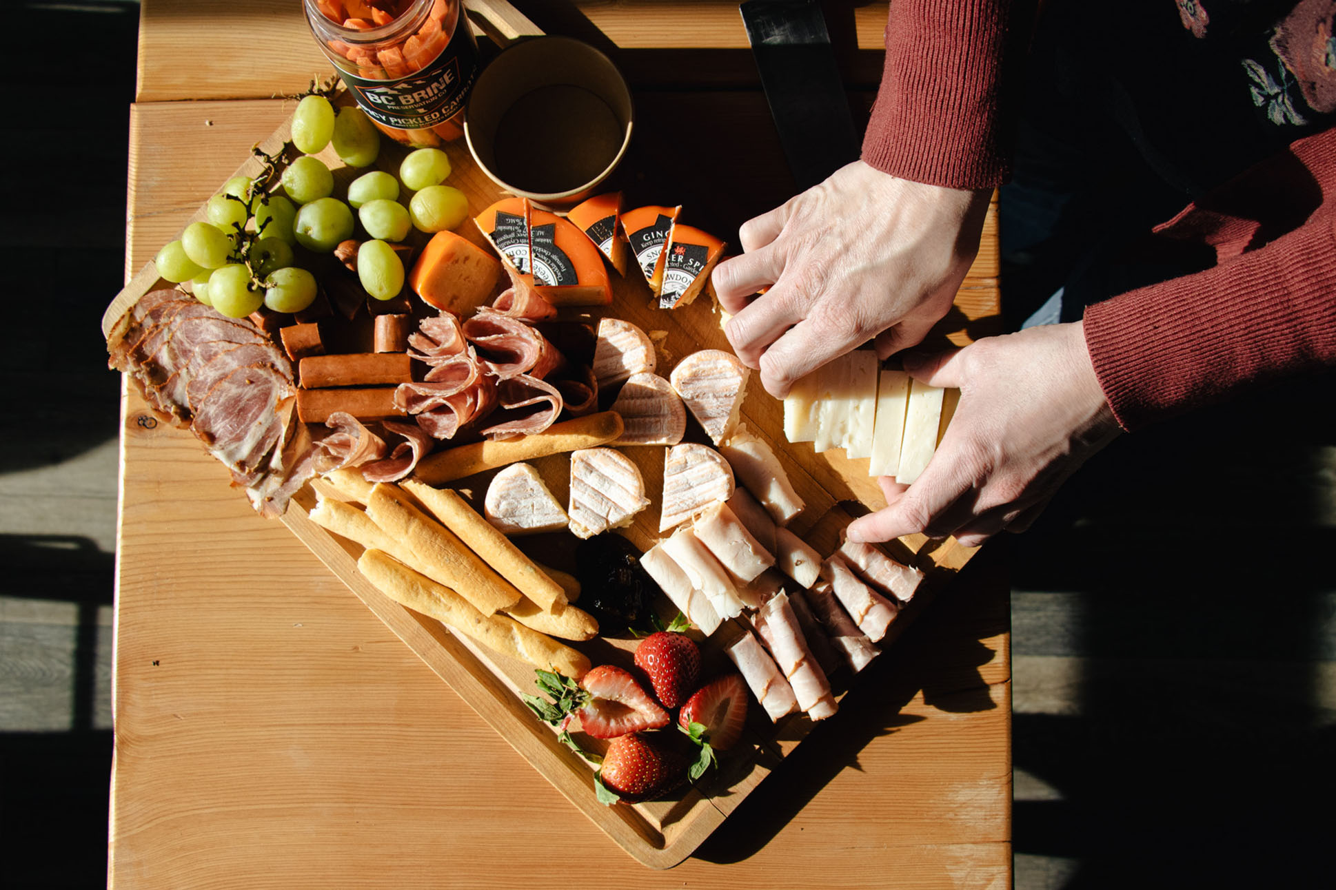 Person placing cheese on a charcuterie board from Ohana Deli.