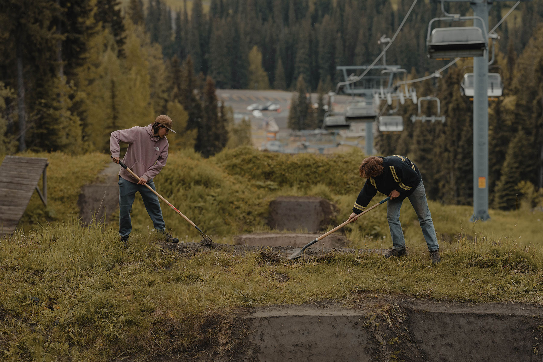 Two trail builders work on a mountain bike jump.