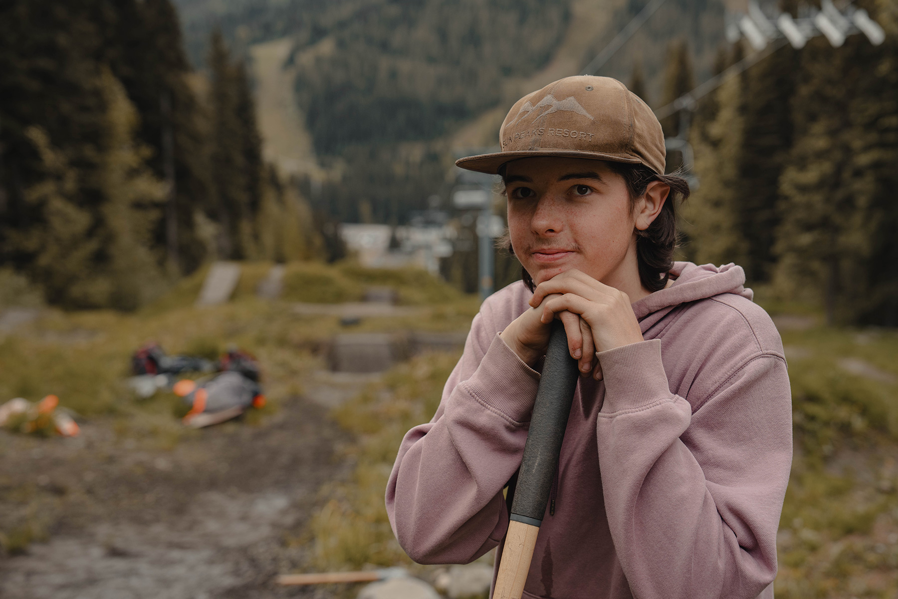 A trail builder rests his chin on the handle of a shovel.