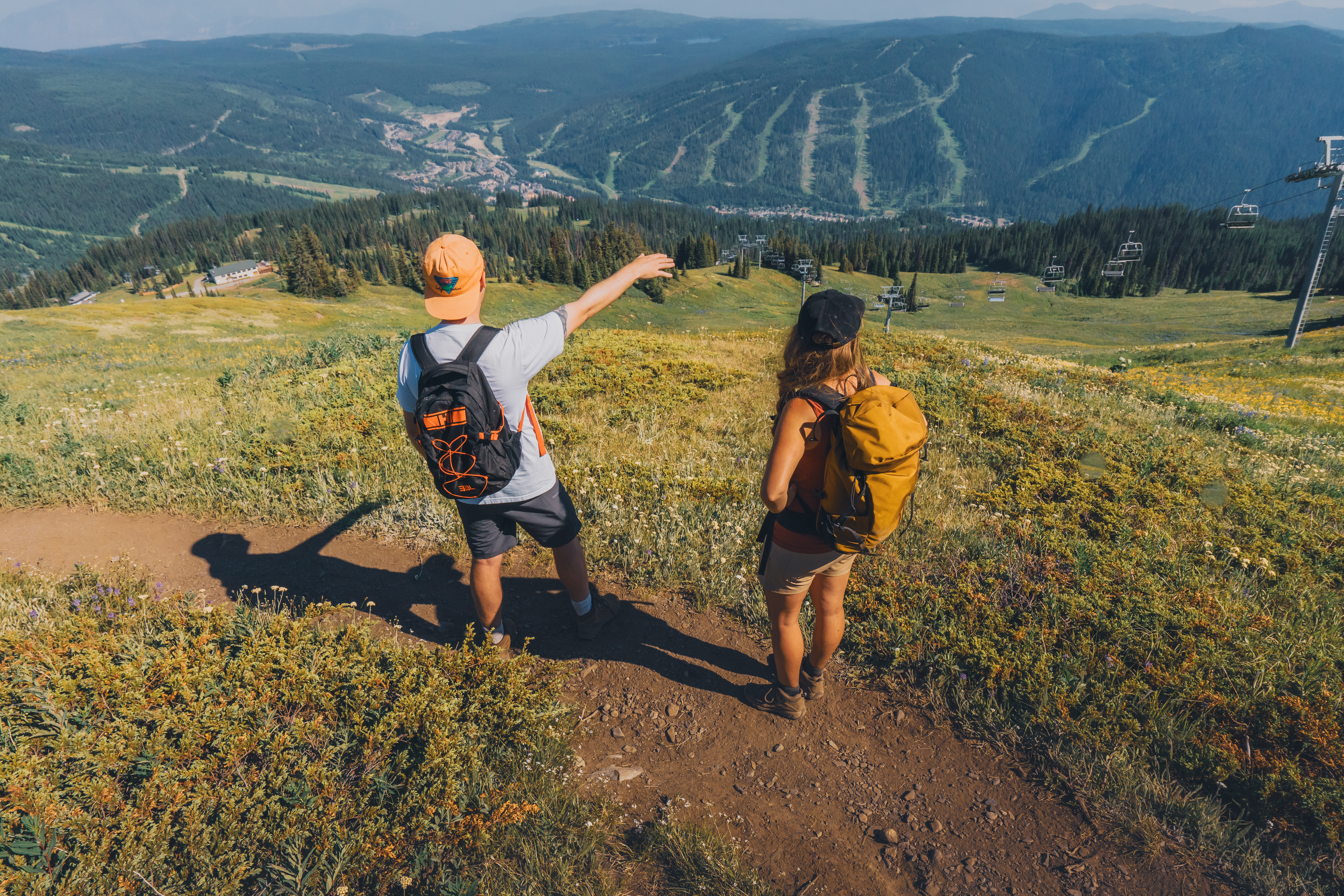 Twop hikers standing on Top of the World trail looking at Sun Peaks Village and mountain scenery