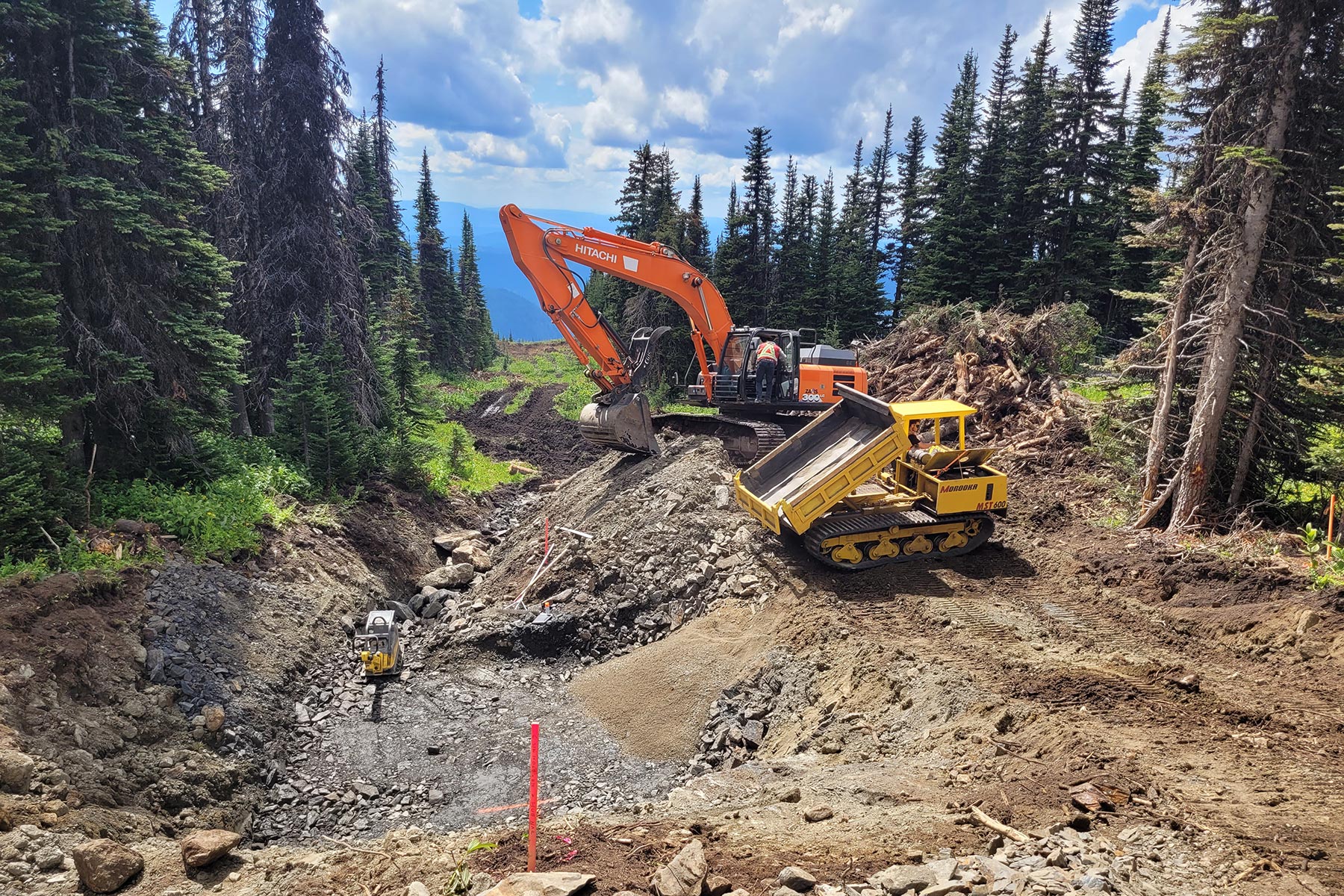 Construction of chairlift tower foundations with excavator.
