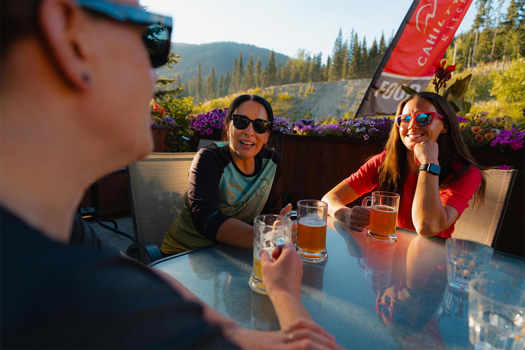 Three woman smiling and drinking on an outside patio in the sun