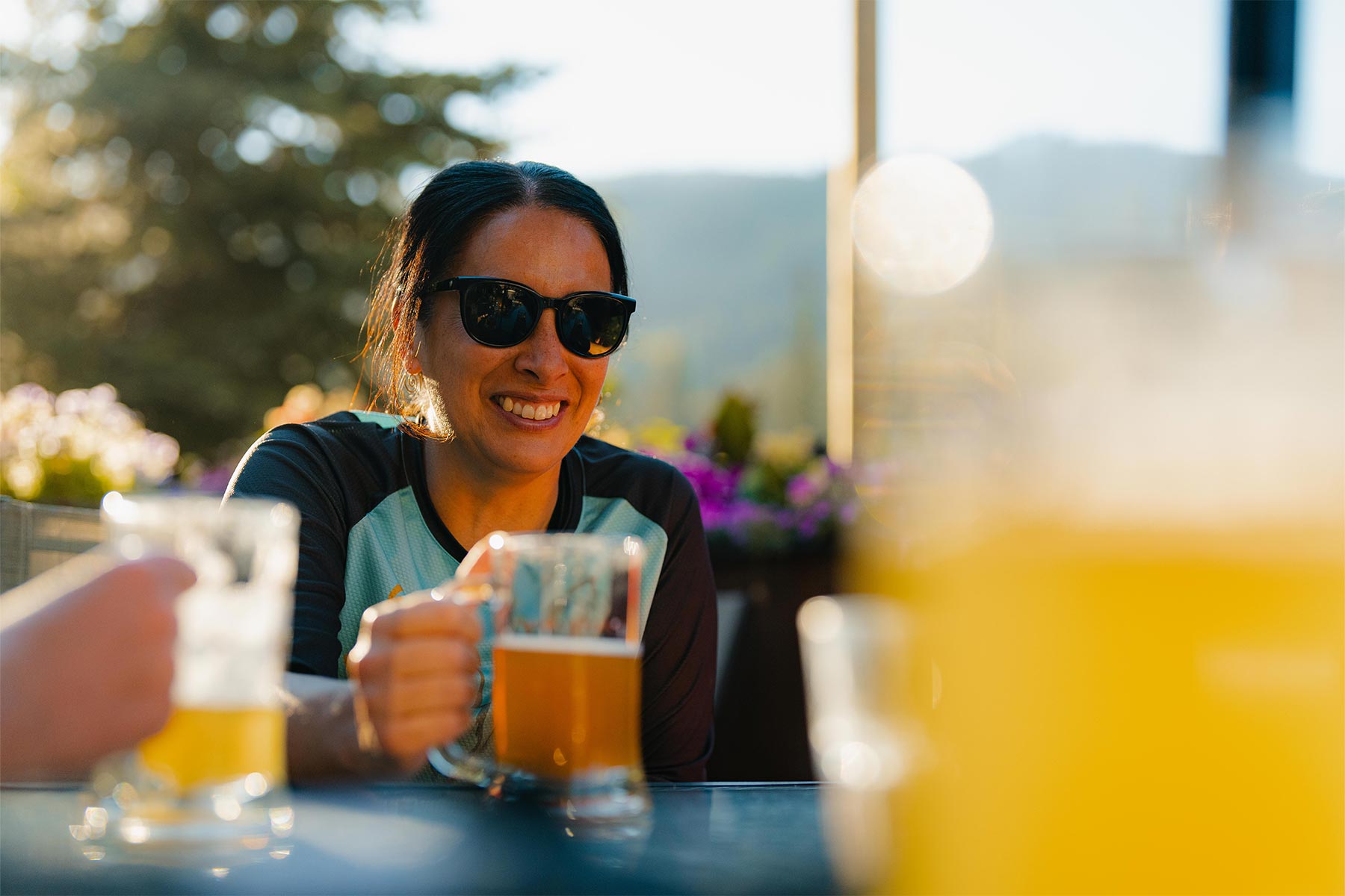 Woman smiling while cheersing a drink on an outside patio in the sun