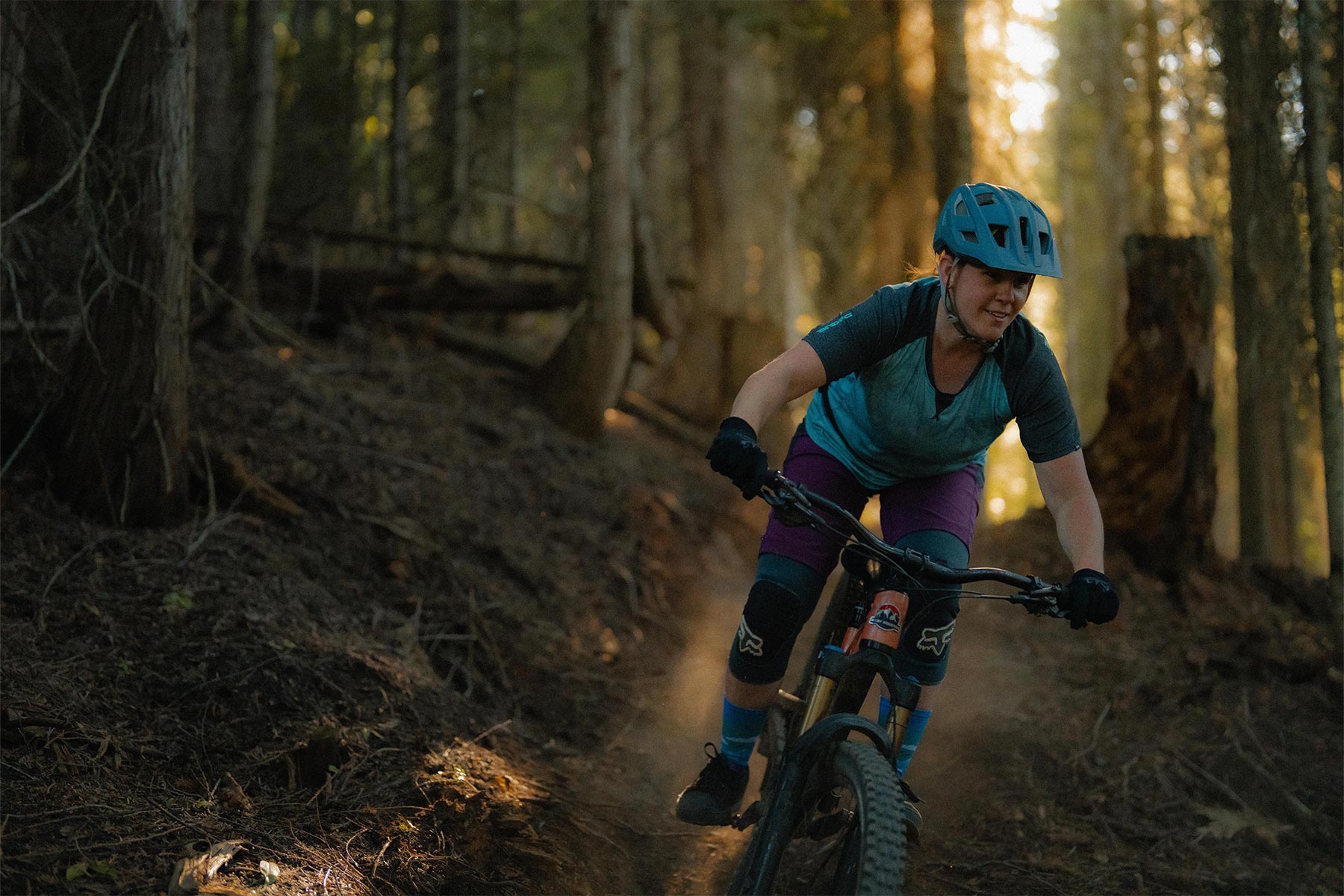 Woman riding her bike down a trail with trees around her