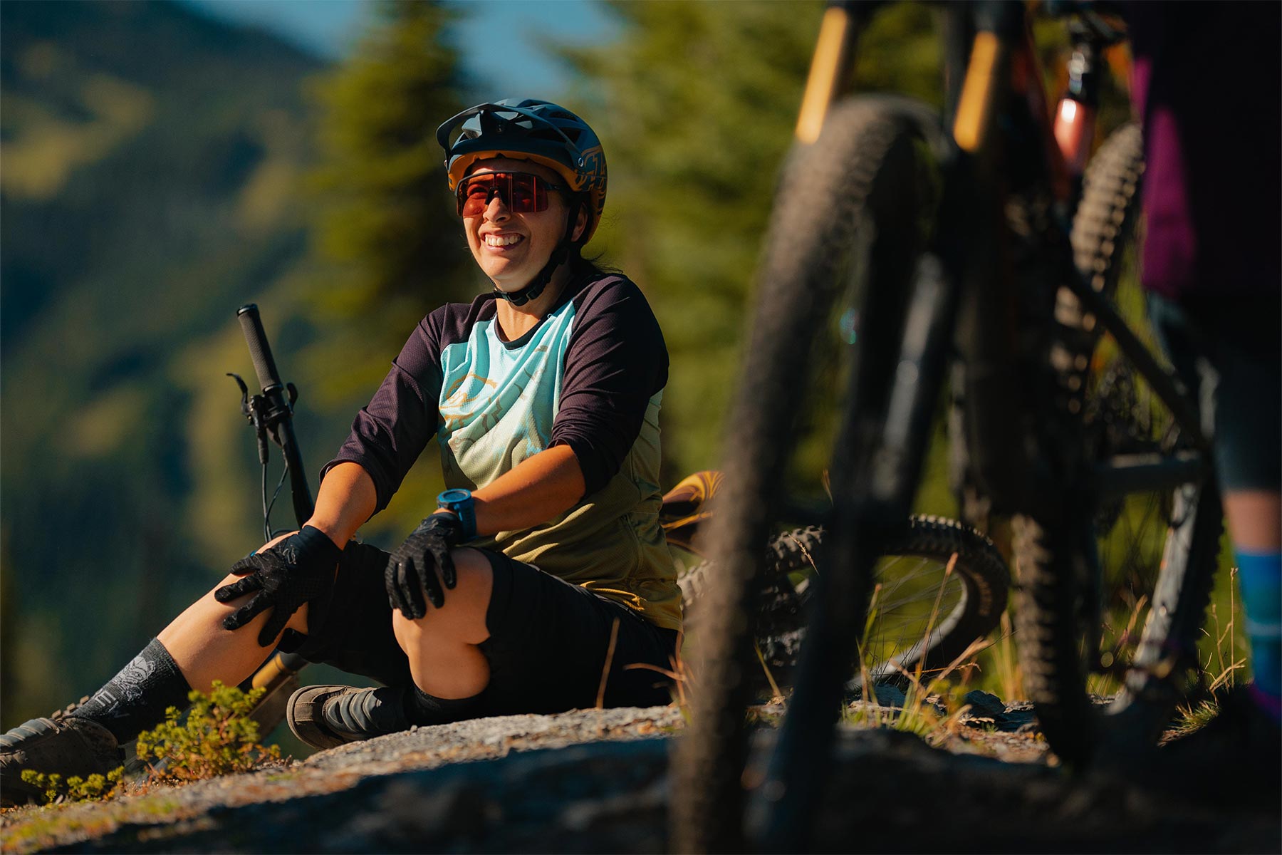 Lady sitting on the ground with her bike smiling