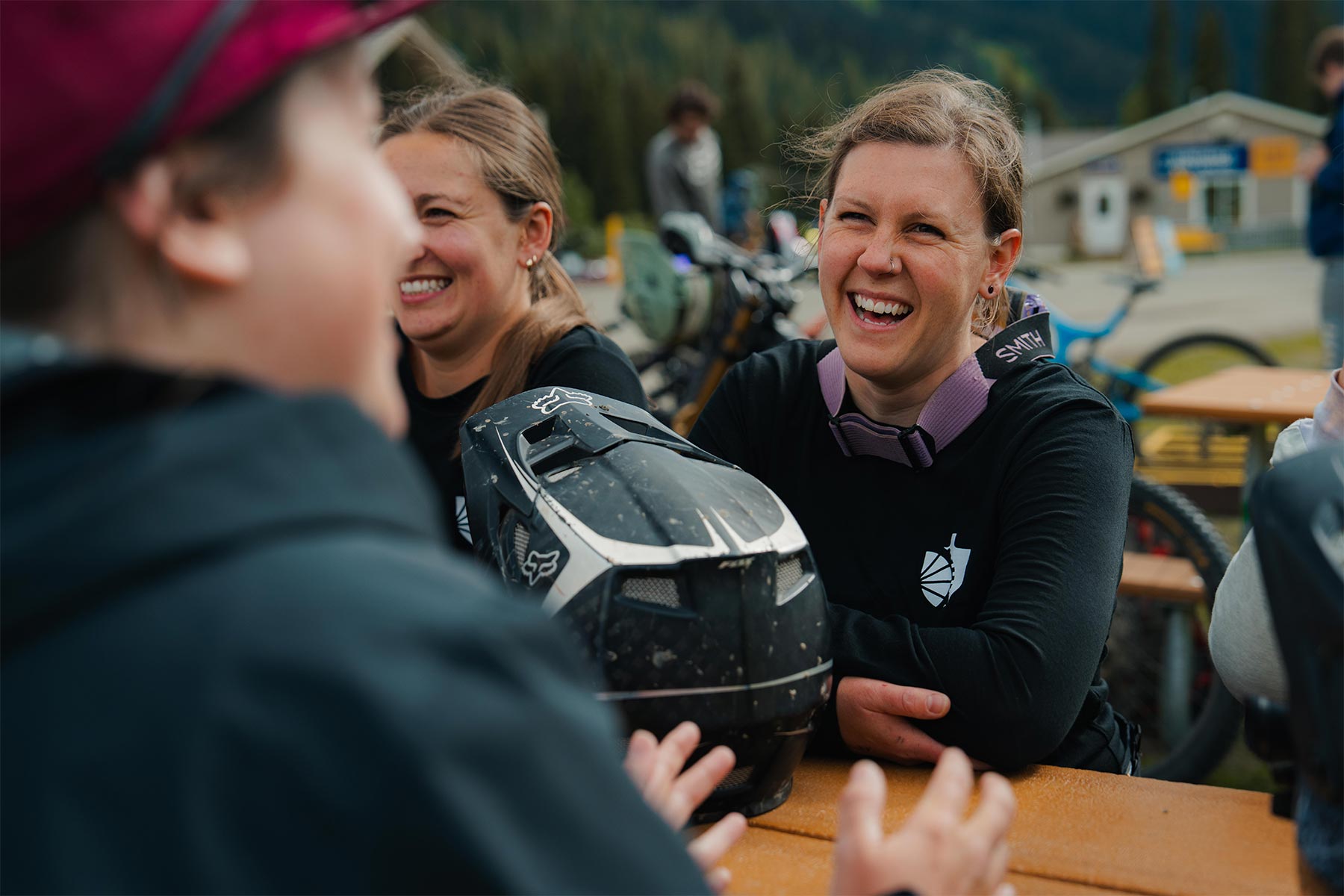 group of ladies laughing out side holding a helmet