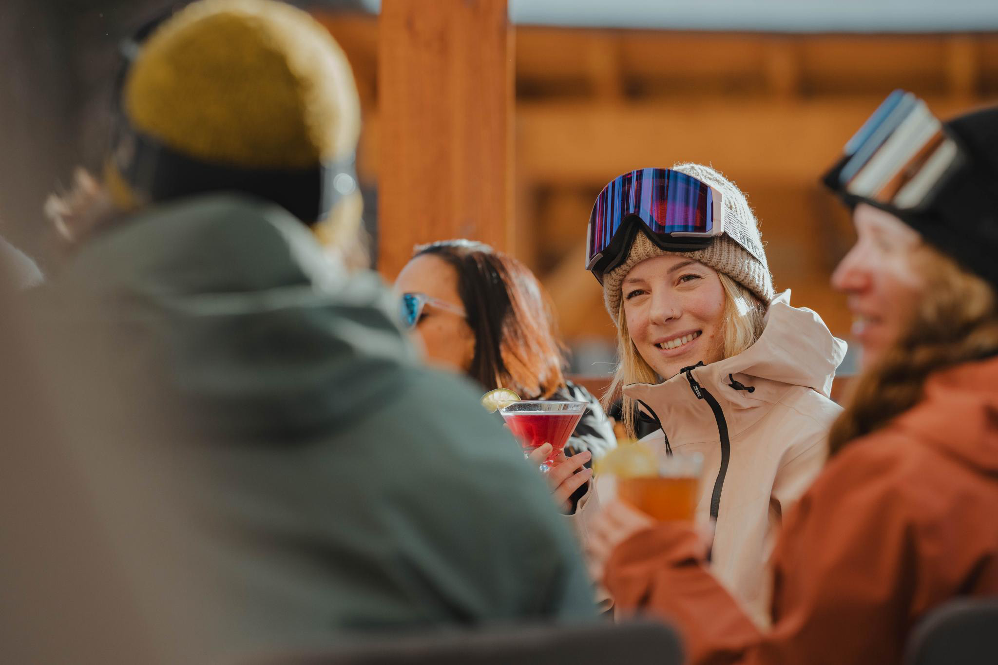Zuzy smiles with a group of friends in ski gear, all enjoying après drinks in the sun.