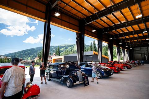 Car show under covered area with mountains in the background