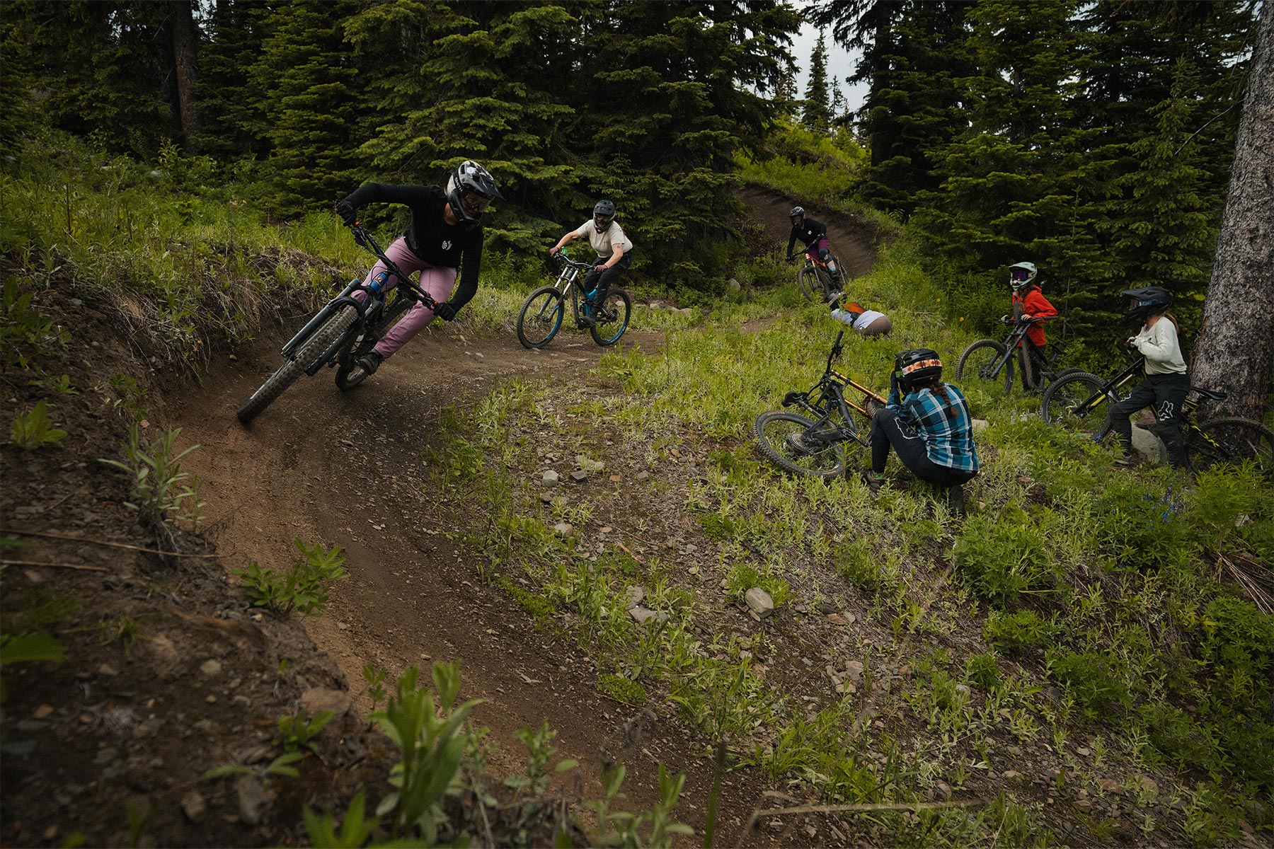 a group of girls biking while some take photos and watch